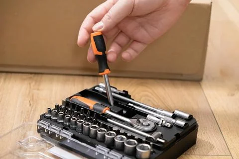 A hand precisely selects an orange-handled screwdriver from a complete comp.. Stock Photos