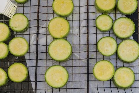 Hand prepares raw sliced vegetables - zucchini, squash, eggplant roasting on the Stock Photos