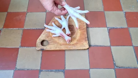 Hand Preparing Fresh Raw Chicken Feet on a Wooden Cutting Board for Cooking Stock Footage 344927916