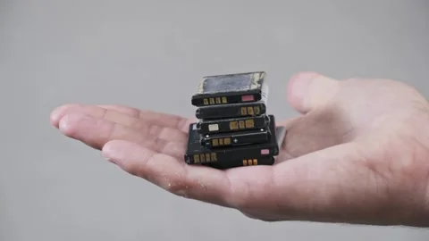 Hand Presenting a Stack of Obsolete Mobile Phone Batteries Stock Footage 315410229