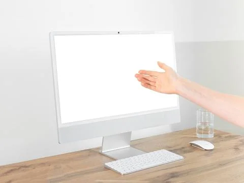 Hand presenting towards blank computer monitor screen mockup at wooden offi.. 写真素材