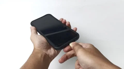 Hand presents a smartphone, poised to connect a USB charger. Stock Footage 313381455
