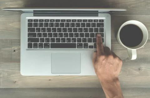 Hand press enter key button with coffee cup on wooden background Foto stock
