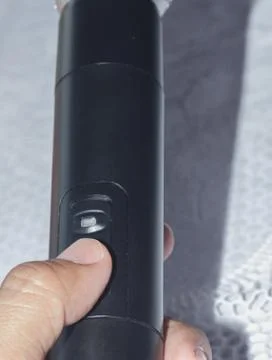 Hand press the power button on the microphone. Stock Photos