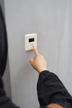 A hand presses a bell button on a wall Stock Photos