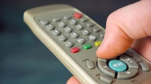 Hand presses up button on the TV remote Fotos de archivo