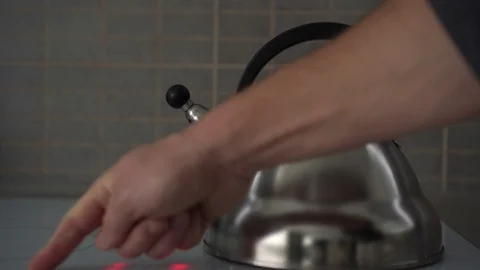 Hand presses buttons to adjust electric stove with kettle Stock Footage 119017452