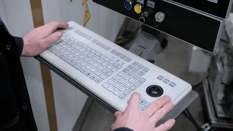 The hand presses the buttons on the control panel of the CNC machine. Factory Stock Footage 172112685