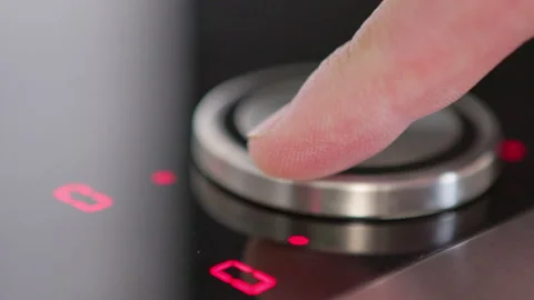 A hand presses the control of a sleek modern induction cooktop with glowing indi Stock Footage 281599657
