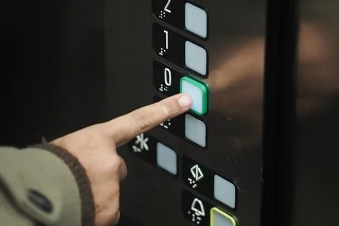 Hand presses elevator button for ground floor Stock Photos
