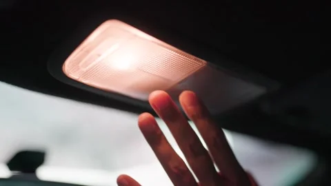Hand presses Lamp of car ceiling button. Woman turns on car lights. Low angle sh Stock Footage 264105400
