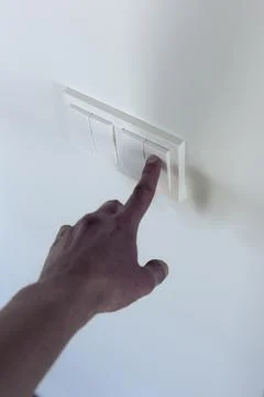 Hand presses a light switch with a finger Stock Photos