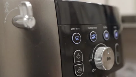 A hand presses the plastic power button on the coffee machine's control panel. Stock Footage 320891419