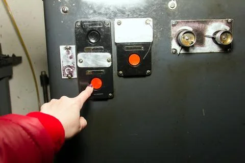 Hand presses the start button at the factory Stock Photos