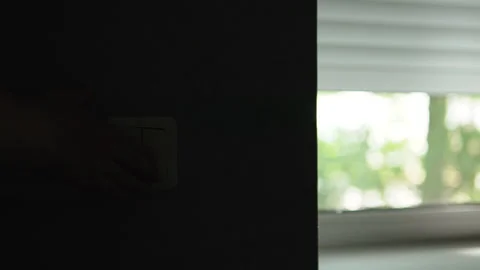 Hand presses switch and roller blinds on windows lower, darkening room. Stock Footage 330489242