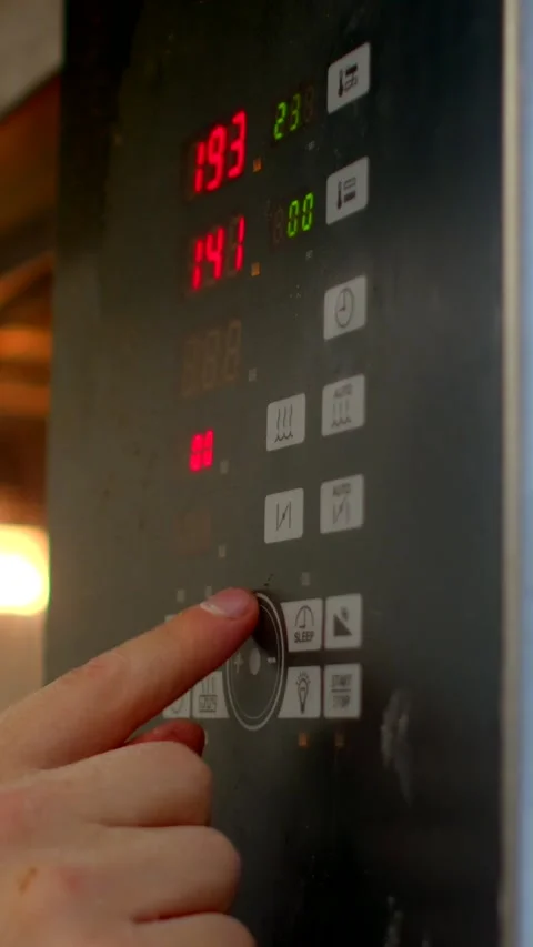 Hand pressing appliance control dial and function buttons with led digit display Stock Footage 345601214