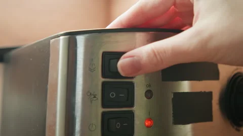 Hand pressing black button on stainless steel appliance control panel with red Stock Footage 343539224