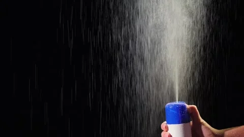 Hand pressing blue spray can releasing fine mist liquid drops against dark .. Stock Footage 335065227
