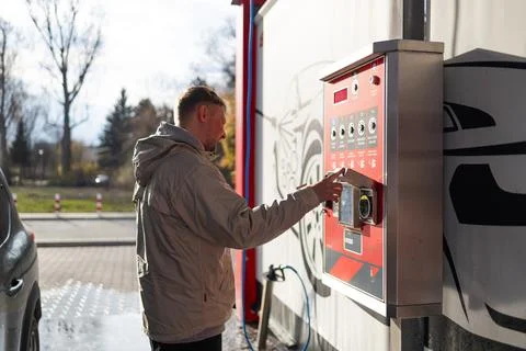 Hand pressing button on automated vending machine at manual carwash station. Stock Photos