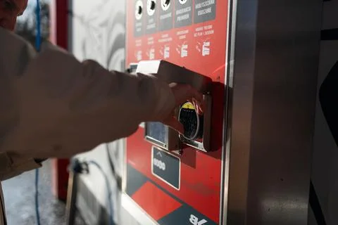 Hand pressing button on automated vending machine at manual carwash station. Stock Photos