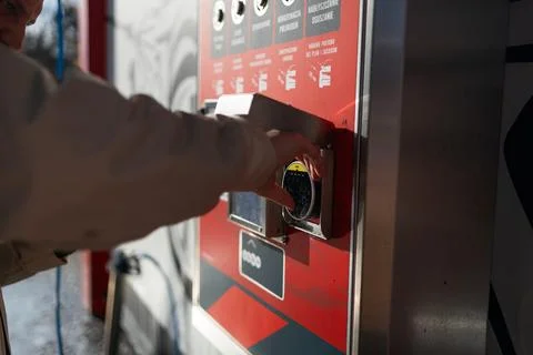 Hand pressing button on automated vending machine at manual carwash station. Stock Photos