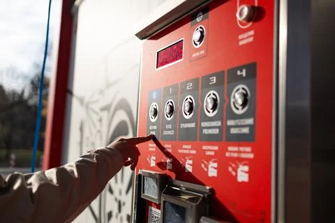 Hand pressing button on automated vending machine at manual carwash station. Stock Photos