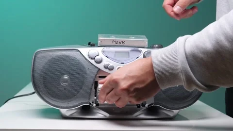 Hand pressing a button on a classic silver boombox, playing a cassette tape Stock Footage 345532121