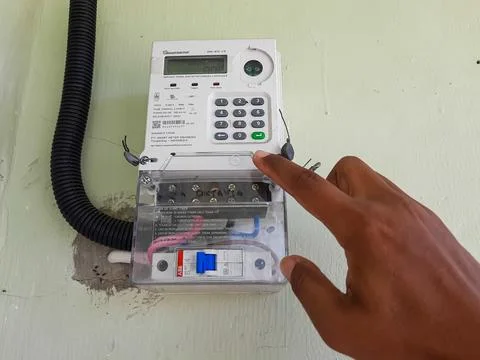 Hand Pressing Button on Electricity Meter to Load PLN Token in Indonesia Fotos de archivo