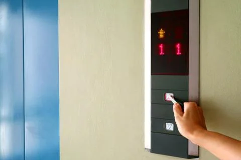 Hand pressing the button of elevator with key for self-sanitization Stockfoto's