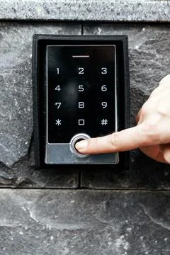 Hand pressing a button on a modern digital keypad mounted on a textured sto.. Stock Photos