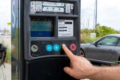 Hand pressing button on parking payment machine beside car Stock Photos