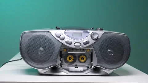 Hand pressing a button on a silver boombox with a cassette tape inserted Stock Footage 345529995