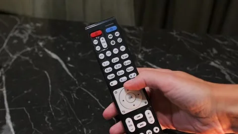 Hand pressing button on TV remote control, close-up of user clicking channel or Stock Footage 333650051