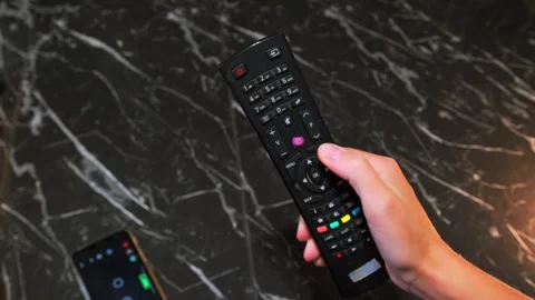Hand pressing button on TV remote close-up, controlling television functions Stock Footage 333650061