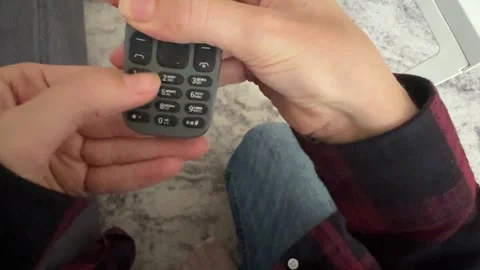 Hand pressing buttons on old mobile phone keypad, retro communication device and Stock Footage 337119884