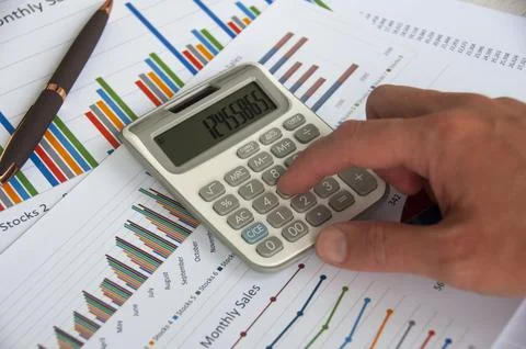 Hand pressing calculator with graph analysis background. Business concept Foto stock