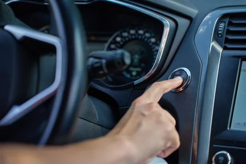 Hand pressing car engine start button inside modern vehicle Foto stock