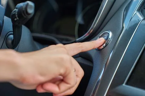 Hand pressing car engine start button inside modern vehicle Stock Photos