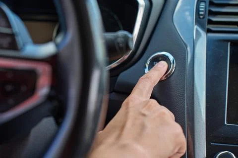 Hand pressing car engine start button inside modern vehicle Stock Photos