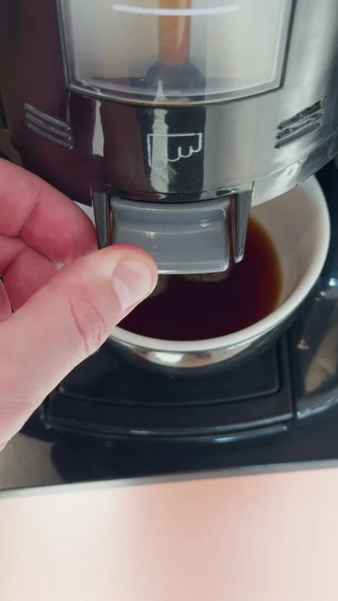 Hand pressing coffee machine button with fresh brewed coffee pouring into cup in Stock Footage 346853780