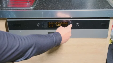 Hand pressing dishwasher buttons close-up view, selecting washing program on 動画素材 333649064