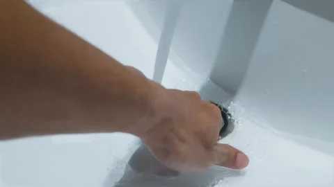 Hand pressing down the drain stopper in a white bathroom sink with running water 스톡 동영상 344091936