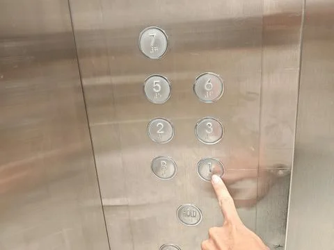 Hand pressing elevator button with Braille markings Stock-Fotos
