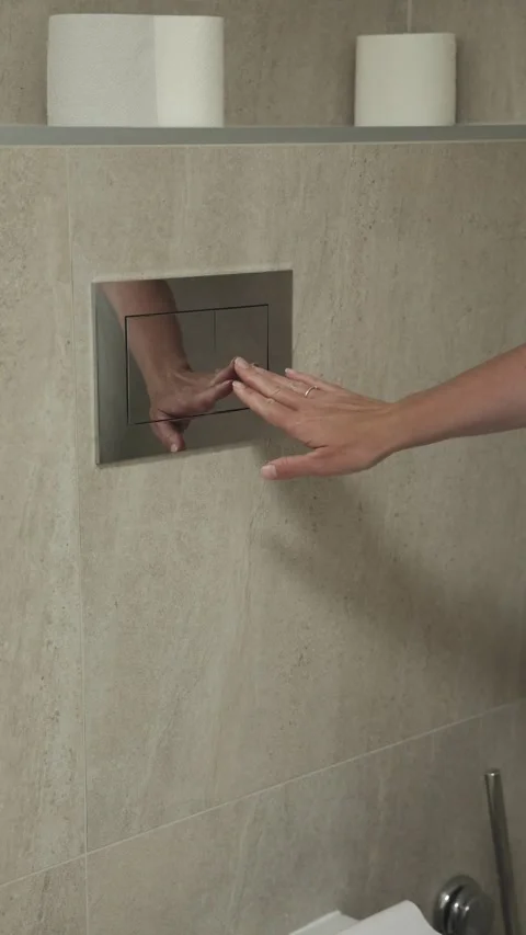Hand pressing flush button on modern toilet, showcasing sleek design and hygiene Video stock 313726017