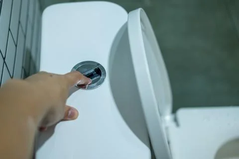 Hand pressing the flush button Stock Photos
