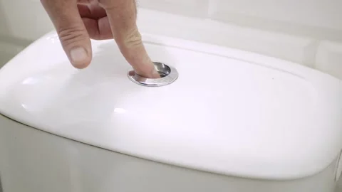 Hand Pressing Flush Button on Toilet Tank to Flush Water in Bathroom Stock Footage 314180674