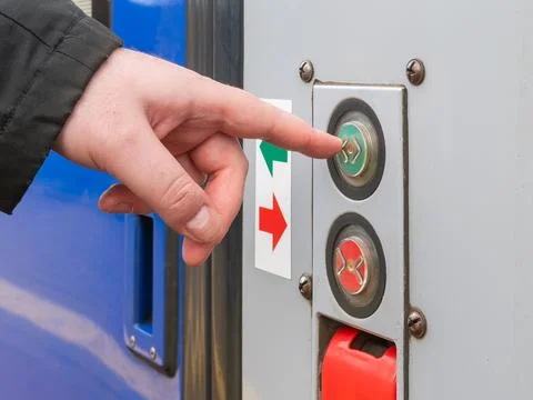 A hand pressing a green button to open a train carriage door, representing Stock Photos