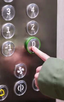 Hand pressing ground floor button in modern elevator interior panel. Foto stock