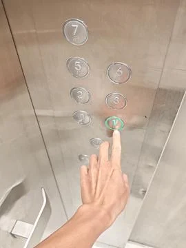 Hand pressing illuminated elevator button with Braille markings Stock Photos