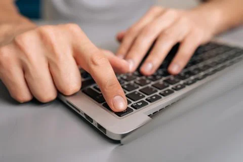 Hand pressing laptop power button in close-up, starting up portable computer on Stock Photos